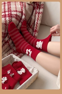 Gros plan de chaussettes rouges rayées avec oursons 3D et nœuds en satin rouge