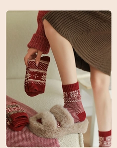 Detail of red festive wool socks with white snowflake patterns and thick knitted texture