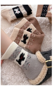 Detail von warmen Fair Isle Socken mit niedlicher Hundestickerei und Wellenmuster
