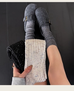 Detailed knit texture of thick wool socks in grey, black, and beige marled yarn
