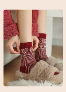 Close-up of thick red wool socks with white snowflake patterns and plush slippers