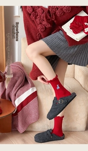 Close-up of red socks with blue giraffe embroidery, ruffled edges and grey felt slippers