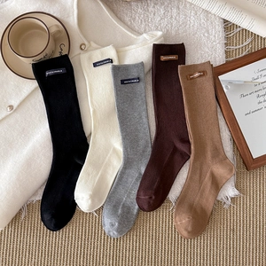 Five pairs of ribbed knit crew socks with leather patches in neutral autumn tones