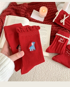 Detail of red festive socks featuring blue cartoon embroidery and elegant ruffle trim