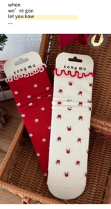 Detail of red and cream floral knit socks with scalloped edges in a wicker basket