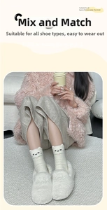 Close-up of white plush thermal socks featuring a cute embroidered cat face pattern