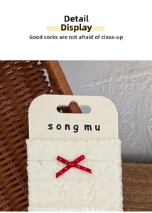 Detail view of off-white cable knit sock with red polka dot bow and scalloped edge