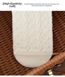 Detail of white knit socks showing elastic loose top and intricate cable pattern