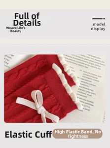 Close-up of red knit socks featuring vintage cable texture and white lace bow detail
