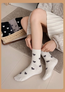 Détail de chaussettes en maille crème avec motif de cœur gris et texture à côtes fines