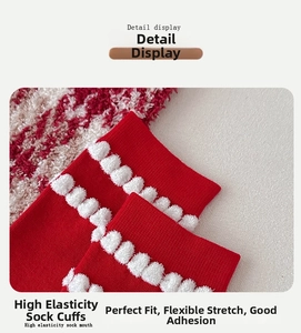 Detail view of red knitted socks featuring high elasticity cuff and decorative white pom poms