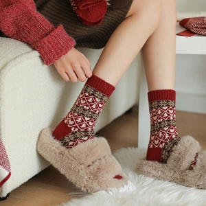 Red Fair Isle Christmas wool socks with festive heart and tree patterns on a model