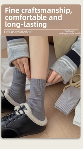 Detailed close-up of grey ribbed knit socks with small embroidery and warm fleece shoes