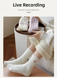 Close-up of soft coral fleece socks with cute cartoon cat and rabbit embroidery detail