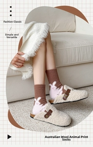 Detail of warm brown socks with pink rabbit heel pattern worn with cozy beige slippers