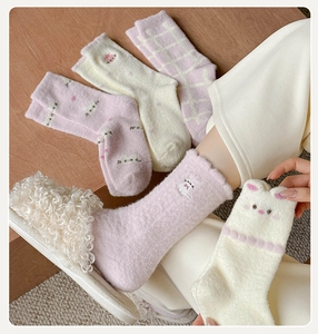 Detailed close-up of soft pink winter socks with cute cat embroidery and ruffle cuffs