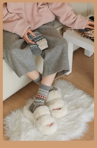 Dettaglio di calze di lana con motivi geometrici e pantofole di peluche bianche calde