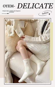 Détail de chaussettes en polaire beige avec broderie animalière et bordure ondulée douce