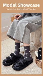 Détail de chaussettes à cœurs gris foncé avec des chaussons noirs à boucles en peluche