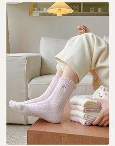Detail view of pink and white plush socks with cute animal embroidery for winter warmth