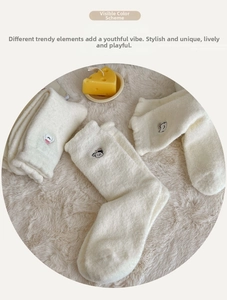 Gros plan sur des chaussettes en peluche blanc crème avec broderies d'animaux mignons