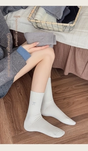 Close-up of white ribbed crew socks with light blue embroidered bow detail and cotton texture