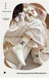 Détail de chaussettes épaisses en peluche crème avec motif ours sur plaid doux