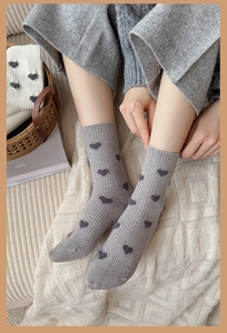 Détail de chaussettes mi-hautes en tricot gris avec motif cœur floqué et bord-côte
