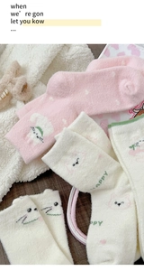 Close-up of soft pink and white fuzzy winter socks with cute cartoon cat and Happy text