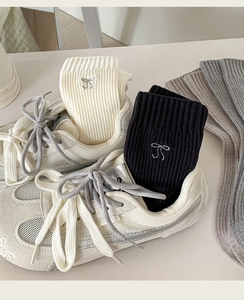 Detail of ribbed knit crew socks featuring elegant bow embroidery in black, white, and grey