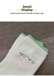 Detail of plush cat motif socks with green trim and warm fleece texture on wood surface