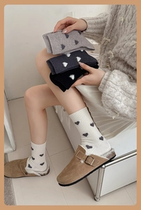 Détail de chaussettes douces à côtes avec motifs de cœur portées avec des sabots en daim