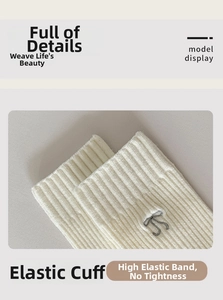 Close-up of cream knit socks featuring elastic ribbed cuffs and dark grey bow embroidery