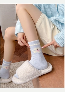 Close-up of blue winter socks with cute knitted puppy design and pink bow detail