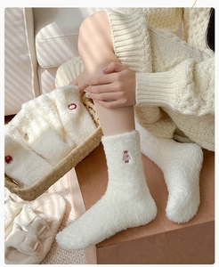 Gros plan de chaussettes blanches en polaire avec broderie mignonne dans un panier tressé