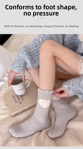 Close-up of soft gray plush socks with heart patterns in a cozy home bedroom setting