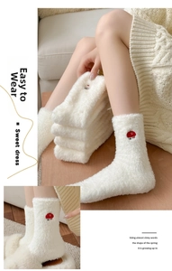 Détail de chaussettes en velours de vison blanc pelucheux avec broderie de champignon rouge