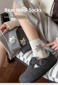 Gros plan détaillé de chaussettes en laine avec broderie ours 3D et bords-côtes élastiques