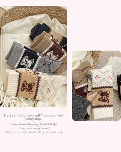 Detail der Strickstruktur von Wollsocken mit süßer Bärenstickerei und geometrischen Mustern