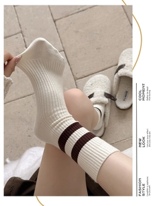 Gros plan de chaussettes blanches côtelées à rayures brunes montrant le tissu élastique