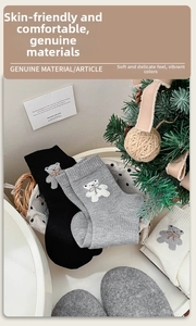 Détail de chaussettes en laine avec broderie ours présentées dans un panier douillet