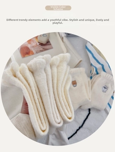 Detail of cream plush socks with cute bear embroidery and thick thermal texture