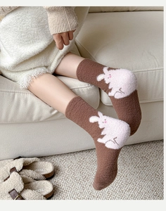 Detailed texture of warm brown plush socks featuring a cute white rabbit jacquard pattern