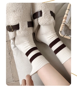 Détail de chaussettes blanches à rayures brunes portées avec des bottes d'hiver