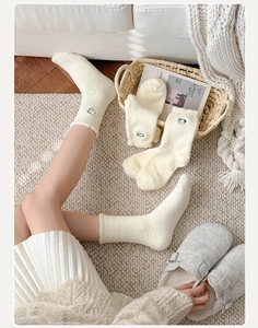 Gros plan de chaussettes thermiques en peluche blanc crème avec broderie panda
