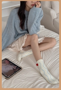 Detail of cozy white knit socks with blue wavy stripes and a red decorative pom-pom