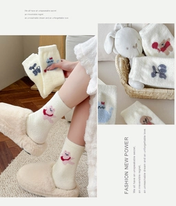 Détail de chaussettes d'hiver pelucheuses avec broderies d'animaux en blanc crème