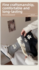 Détail de chaussettes en laine tricotées avec broderie ours en gris, blanc et noir