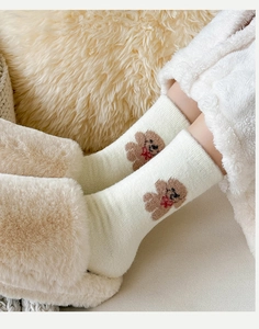 Détail de chaussettes en peluche blanc crème avec motif d'ours et chaussons doux