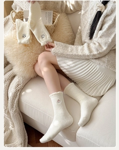 Détail de chaussettes d'hiver en peluche crème avec broderie panda et bords ondulés